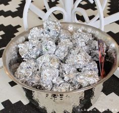 a bowl filled with silver foil sitting on top of a table next to a black and white checkered floor