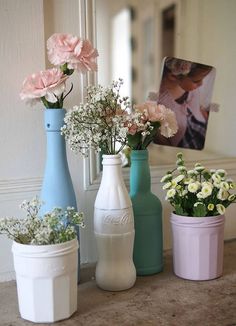 four different colored vases with flowers in them