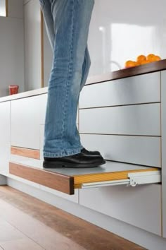 a person standing on top of a drawer with their feet in the drawer and an orange