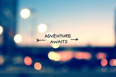 the words adventure awaits are written on a glass window with blurry city lights in the background