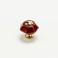 a red and gold colored knob on a white surface with the top part of it turned upside down