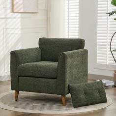 a green chair sitting on top of a rug in a living room next to a potted plant