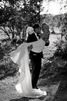 a man in a suit and tie holding a woman in a wedding dress while she holds her