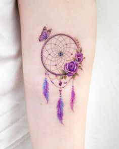 a woman's arm with a tattoo on it that has flowers and a dream catcher