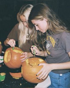 two girls carving pumpkins for halloween