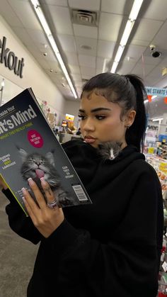 a woman holding up a book in a store