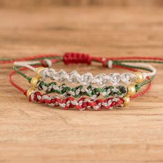 three bracelets with different colored cords on top of a wooden table next to each other