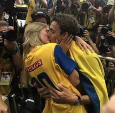 two soccer players are hugging each other in front of a crowd with cameras around them