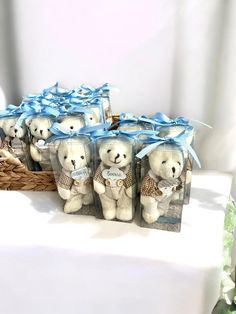 a bunch of teddy bears sitting on top of a table next to some baskets with blue bows