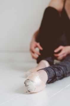 a woman is sitting on the floor with her leg wrapped around an object in front of her