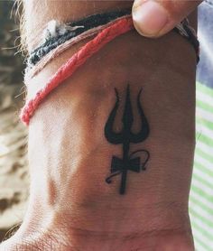 a person with a tattoo on their wrist holding onto the wristband that has a cross and two horns on it