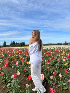 a pregnant woman standing in a field of tulips