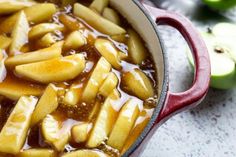 an apple cider filled with sliced apples and caramel sauce in a red pot