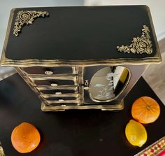 an old fashioned black and gold dresser with oranges