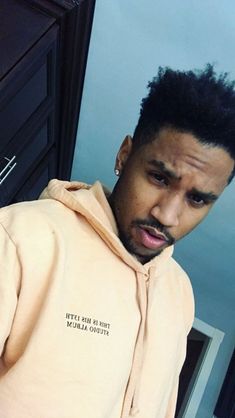 a man with an afro standing in front of a mirror wearing a yellow hoodie