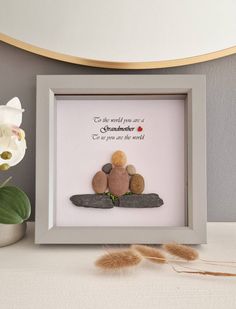 two pebbles sitting on top of rocks in a shadow box with a flower