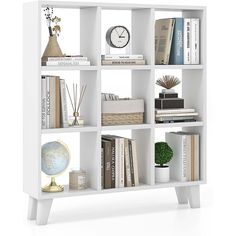 a white book shelf with books and other items on it's shelves in front of a clock