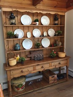 an old wooden hutch with plates and bowls on it's shelf, along with other items