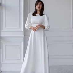 a woman wearing a white dress with long sleeves