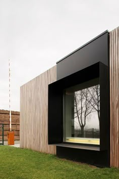 an open window in the side of a wooden building on grass next to a fire hydrant