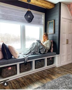 a woman sitting on a window sill reading a book