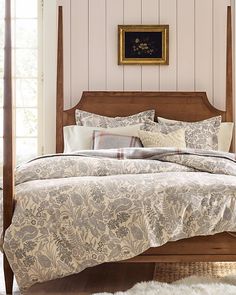 a bed with a wooden headboard and foot board in front of a painting on the wall