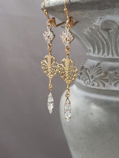 These dainty earrings feature ornate Art Deco style filigree brass connectors and sparkling clear glass beads. The elegant brass connectors are detailed and textured on the front and hollow on the back; lightweight yet sturdy. These earrings measure 3 inches long and hang from gold plated lever back plated ear wires. Perfect delicate earrings to complete a vintage inspired wedding look. ABOUT THIS COLLECTION The sophisticated style of the Roaring Twenties is timeless. The sparkling crystal and luminous pearl jewels in this collection are perfect for your 1920s inspired wedding or just your everyday wardrobe. I invite you to browse my complete Art Nouveau inspired collection here: https://www.etsy.com/shop/BohemeBijou?ref=simple-shop-header-name&listing_id=799784165§ion_id=30429750 1920s Inspired Wedding, Flapper Jewelry, 1920s Earrings, 1920s Accessories, Wedding Earrings Vintage, Bride Vintage, 1920s Jewelry, Art Nouveau Weddings, Vintage Gold Earrings