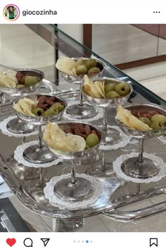 several glasses filled with olives and chips on top of a glass serving platter