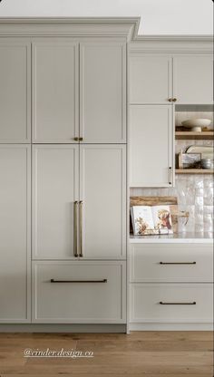 a kitchen with white cabinets and wood flooring is pictured in this image, there are no people or objects on the cabinet doors