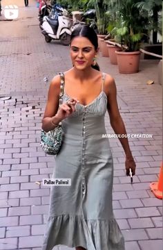 a woman in a gray dress walking down the street