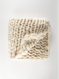 a white knitted blanket on top of a white surface with a knot in the middle