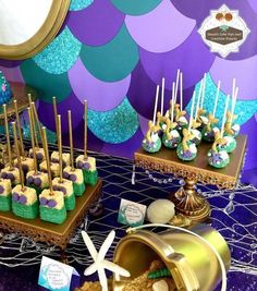 there are many desserts on the table with purple and blue decorations in front of them