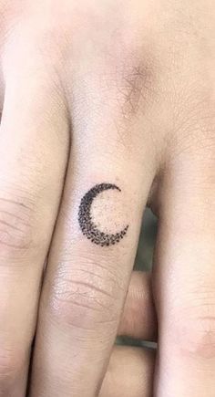 two fingers with small tattoos on them, one has a crescent and the other has a star