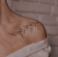 a woman with a tattoo on her shoulder is wearing a white dress and has flowers in it