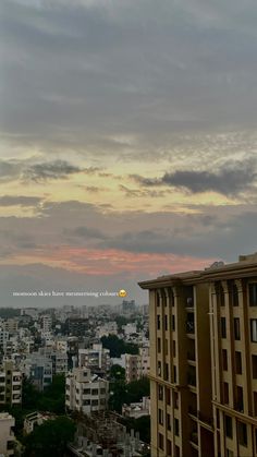 the sun is setting over an urban area with tall buildings in the foreground and clouds in the background