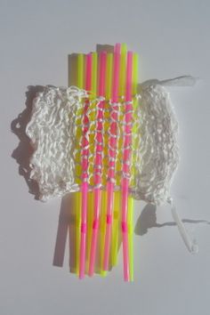 several pink and yellow toothbrushes are lined up on a white surface with crochet