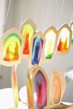 several colorful objects are hanging from strings in the shape of rainbows and people on them