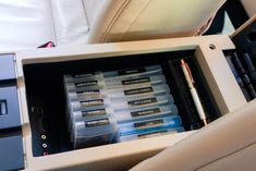 the inside of a car with several pens and pencils in its storage compartment next to an electronic device