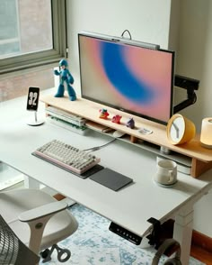 a computer desk with a monitor, keyboard and mouse on it in front of a window