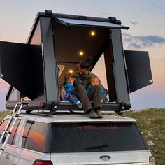 a man and two children are sitting on the roof of a vehicle with their back doors open