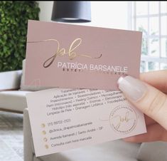 a person holding up a business card with gold foil on the front and back of it