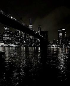 black and white photograph of the city skyline at night with lights reflecting off water in front of it