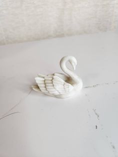 a white swan figurine sitting on top of a table next to a wall