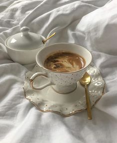 a cup of coffee sitting on top of a white saucer next to a spoon