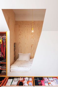 a bed sitting inside of a bedroom next to a wooden shelf filled with clothes and other items