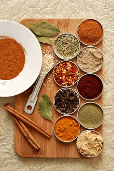 various spices are arranged in bowls on a cutting board