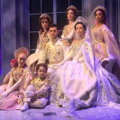 a group of people sitting on top of a bed in dresses and tiaras,