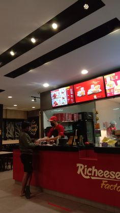 a man standing in front of a fast food restaurant with menus on the wall