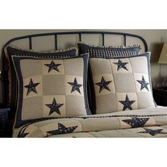 a bed with blue and white quilted stars on the pillow cases, along with a night stand