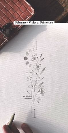 a person is drawing flowers on paper with a pen and inking it in front of them